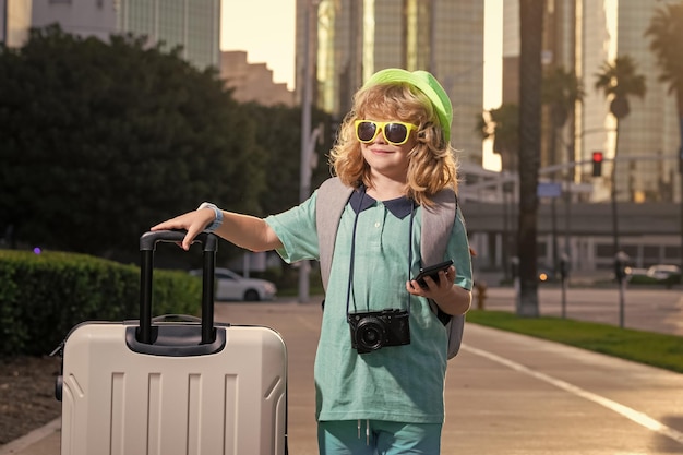 Child with travel suitcase on vacation Kids travel and adventure concept Child boy going on vacation holding luggage travel bag outdoor