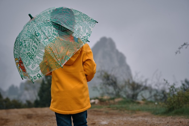 child with umbrella and yellow jacket