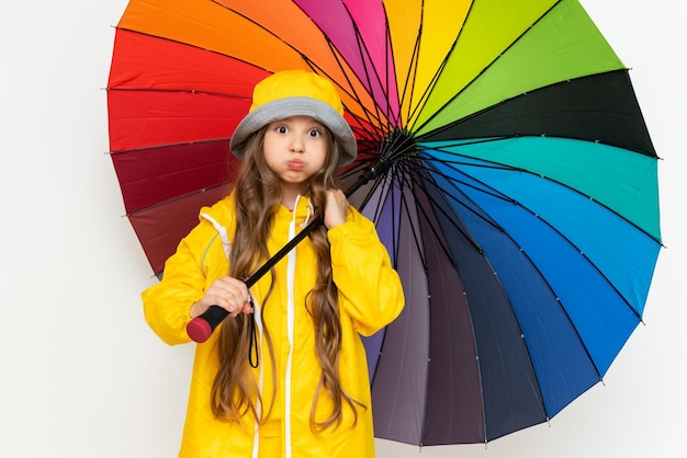 A child with an umbrella and a yellow raincoat The beautiful little girl puffed out her cheeks and opened her eyes wide