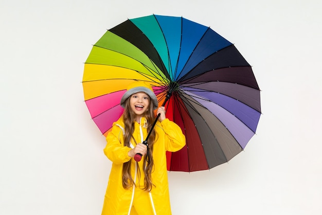 A child with an umbrella and in a yellow raincoat and panama hats Beautiful little girl with long hair on a white isolated background