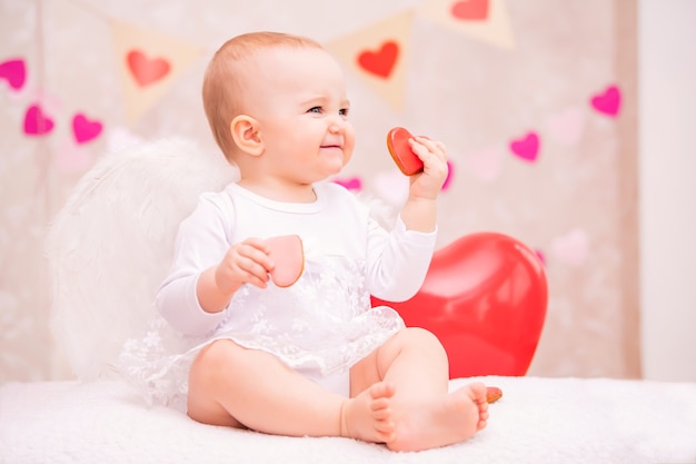 Child with white feather wings holds a red balloon in the shape of a heart