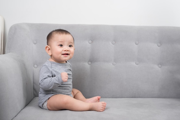 Childhood babyhood and people concept happy little baby girl sitting on sofa at home