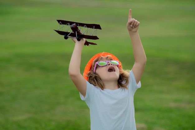 Childhood on countryside Kid playing with toy airplane and dreaming future Happy boy pilot play with airplane outdoors