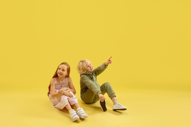 Childhood and dream about big and famous future Boy and girl isolated on yellow studio background