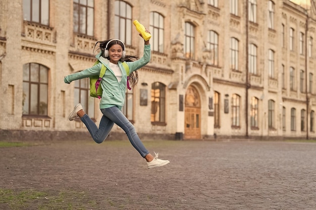 Childhood happiness active and carefree happy child jump in headphones back to school teen girl hold sport bottle water balance in body time for lunch health hydration healthy lifestyle