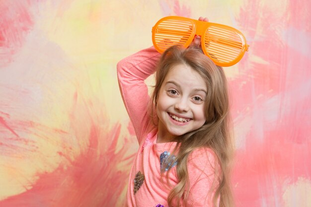 Childhood and happiness. Child girl on colorful background. Small girl in fashionable summer orange glasses. beauty and fashion. glasses on girl kid with happy face.