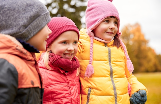 childhood, leisure, friendship and people concept - group of happy kids hugging in autumn park