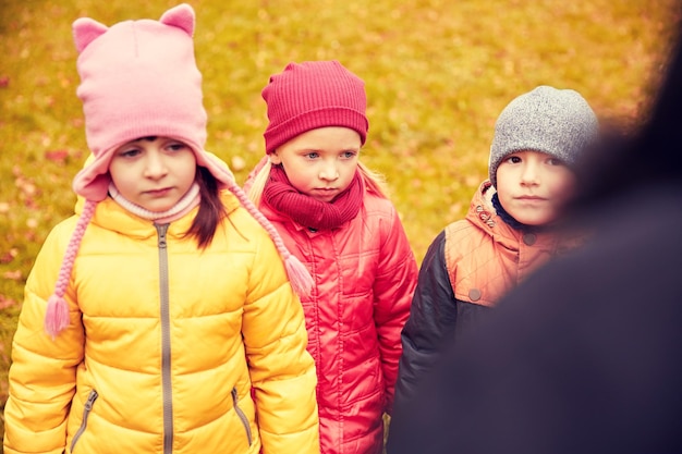 childhood, leisure, friendship and people concept - group of sad kids being blamed for misbehavior in autumn park