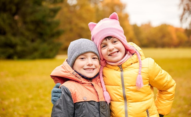 childhood, leisure, friendship and people concept - happy little girl and boy in autumn park