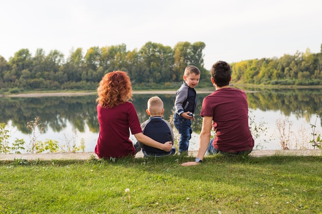 Childhood and nature concept - Family with little sons sitting on the green grass.