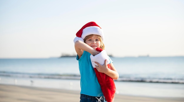 Childhood and new year cute baby boy in red santa hat with christmas stocking on sunny winter day on