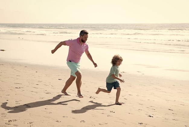 Childhood and parenting father and son running on summer beach family travel weekend and vacation