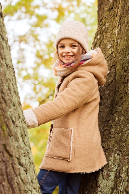 childhood, season and people concept - smiling little girl in autumn park