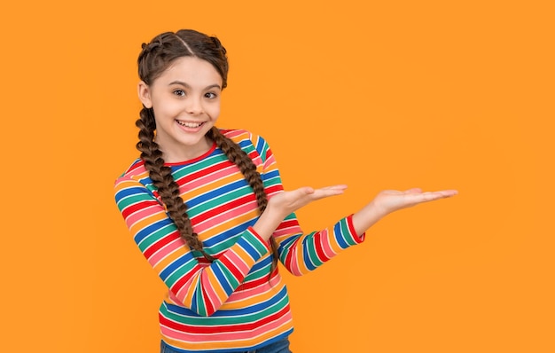 Childhood studio shot of teen girl presenting product concept of childhood teen braided girl