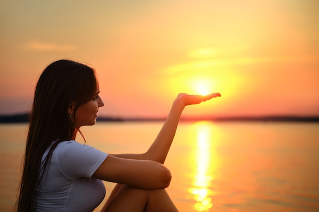 Childish woman holds the sun on palm of her hand