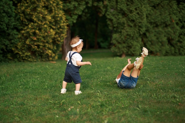 Photo children are having fun in the park on the lawn one girl fell and her sister runs to help