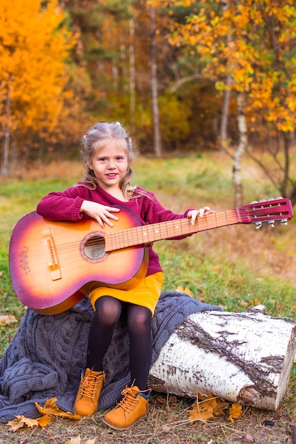 children in the autumn forest on a picnic grill sausages and play the guitar