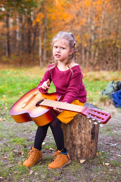 children in the autumn forest on a picnic grill sausages and play the guitar