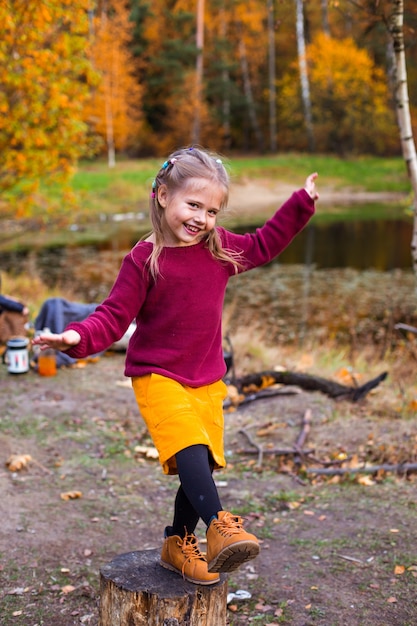 children in the autumn forest on a picnic grill sausages and play the guitar