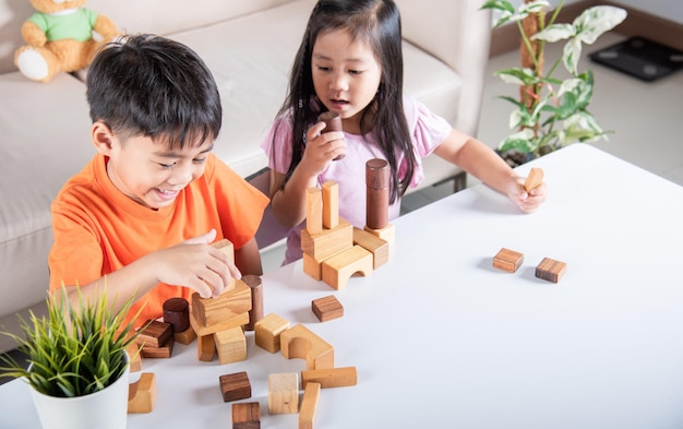 Children boy and girl playing with constructor wooden block building