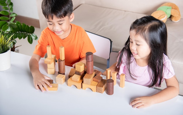 Children boy and girl playing with constructor wooden block building