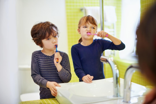 Children brushing teeth in home bathroom with toothbrush for hygiene and clean mouth Oral healthcare or fresh breath kids grooming while bonding and wellness with dental care at sink for dentist