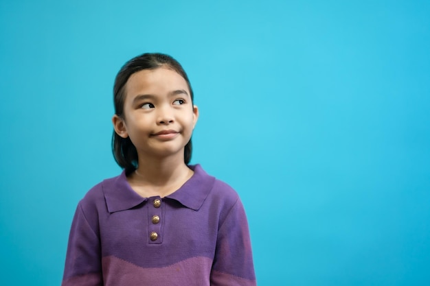 Children close up photo of cute and cheerful people, looking and smile on blue pastel background