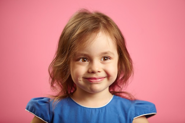 Children closeup portrait of beautiful girl with pretty eyes on isolated pink background