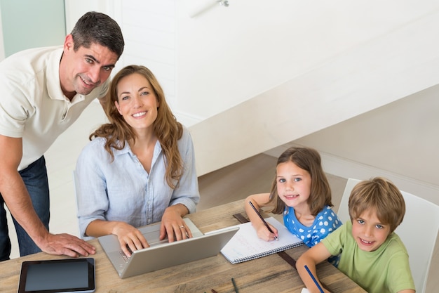 Children coloring while parents using laptop