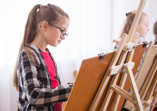 Children draw on an easel in art school.