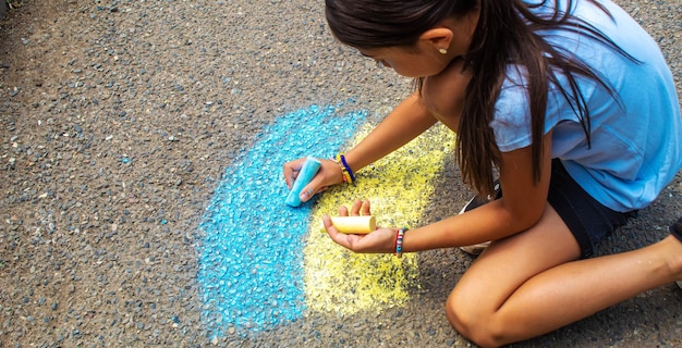 Children draw the Ukrainian flag house on the pavement Selective focus