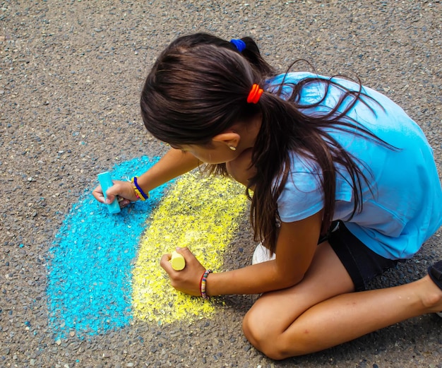 Children draw the Ukrainian flag house on the pavement Selective focus