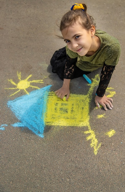 Children draw the Ukrainian flag house on the pavement Selective focus