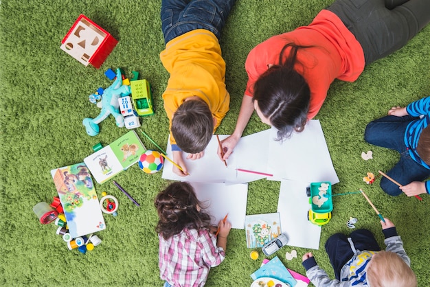 Children drawing and playing on carpet