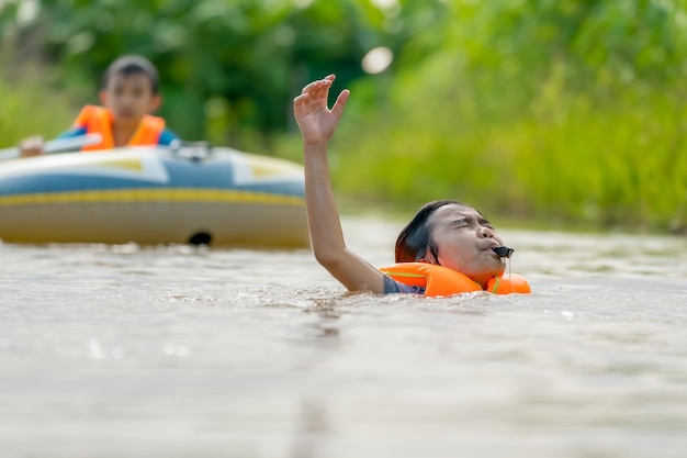 Children drowning the river and blowing whistle show sign for helping and save life