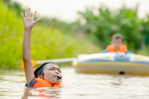 Children drowning the river and blowing whistle show sign for helping and save life