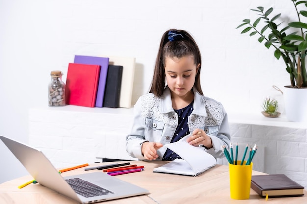 children, education and distant learning concept - little student girl with laptop computer at home