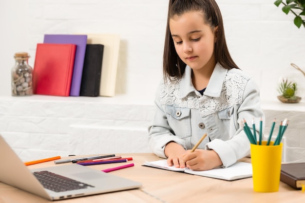 children, education and distant learning concept - little student girl with laptop computer at home