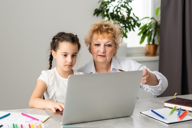 Children and education, teacher or grandmother teaching with notebook by internet to girl.