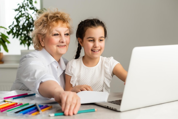 Children and education, teacher or grandmother teaching with notebook by internet to girl.