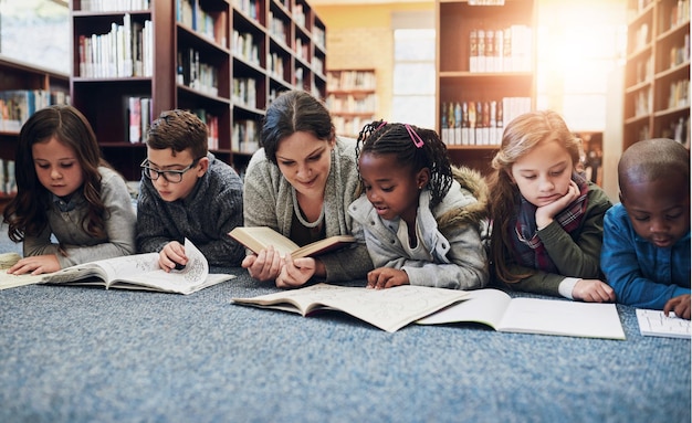 Children education and teacher with books on library floor for reading learning and teaching Study school and woman with kids for storytelling help and fantasy language and skill development