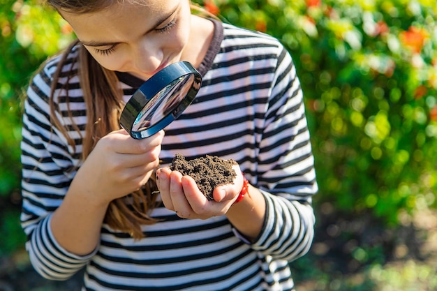 Children examine the soil with a magnifying glass Selective focus