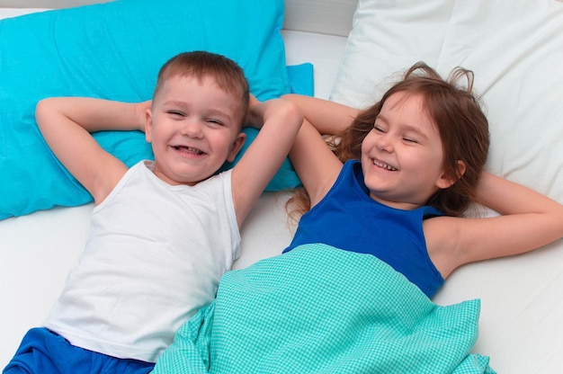 Children fool around in bed. Close-up of happy children playing at home on the bed. The concept of family holiday weekend.