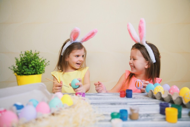 Children in fun paint and decorate easter eggs while wear bunny ears preparing for easter