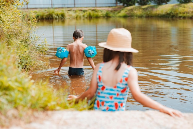 Children have fun and play in the water in a pond outside the city in the village on summer holidays