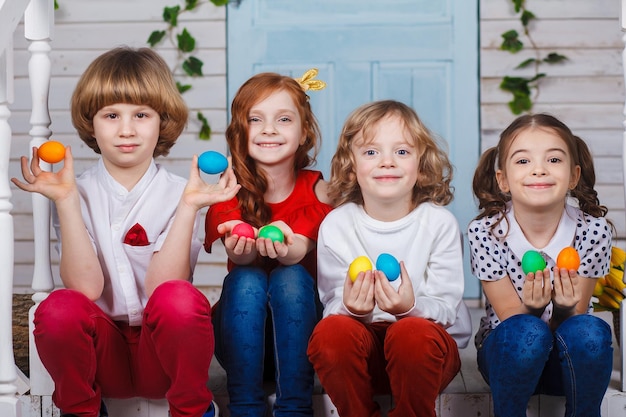 Children holding easter eggs. Beautiful children sit near the basket with tulips and hold Easter eggs in their hands. Funny moments