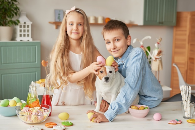 Children holding Easter eggs at the kitchen on a dog