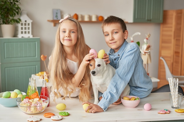 Children holding Easter eggs at the kitchen on a dog