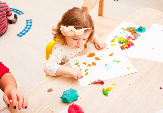 Children is playing with modeling clay on the table