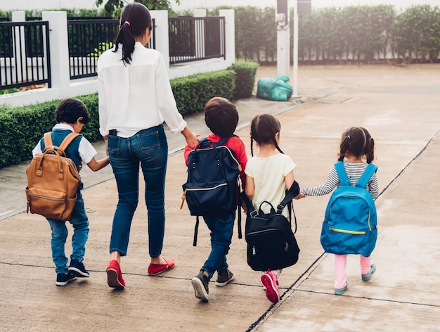 Children kid son girl and boy kindergarten walking going to school holding hand with mother mom